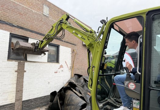 wethouder Merijn Scheifes verwijdert met een sloopkraan de eerste stenen