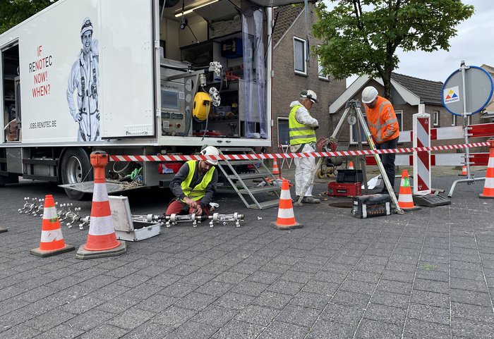 Het bedrijf bezig met het riool rondom een put in de straat