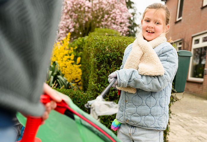 Meisje steekt met afvalprikker afval in een vuilniszak